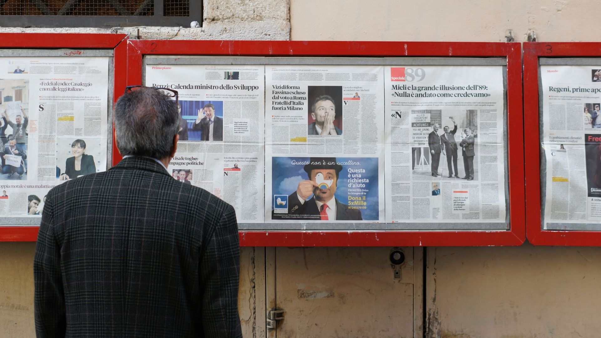 homem olhando para painel de noticias com jornais google news